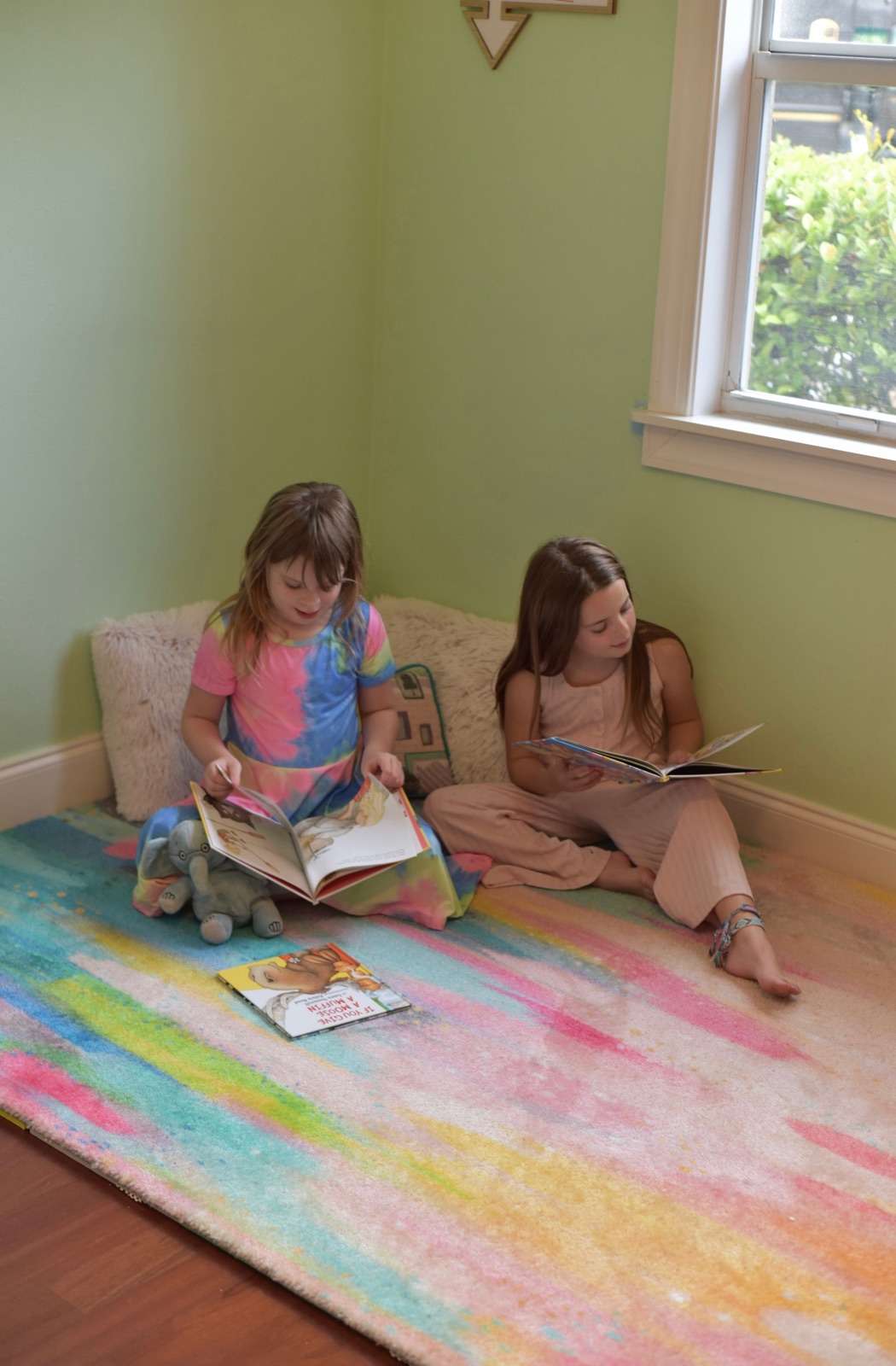 Two children reading books together in a cozy reading corner