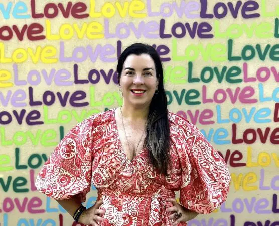 Shannon Hooley standing in front of a wall with the word love
